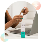 Woman using dropper of Aspen Green Extra Mint CBD Oil at desk
