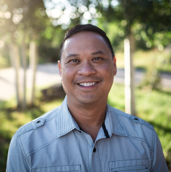 Kyle Chong smiling outdoors with trees in the background